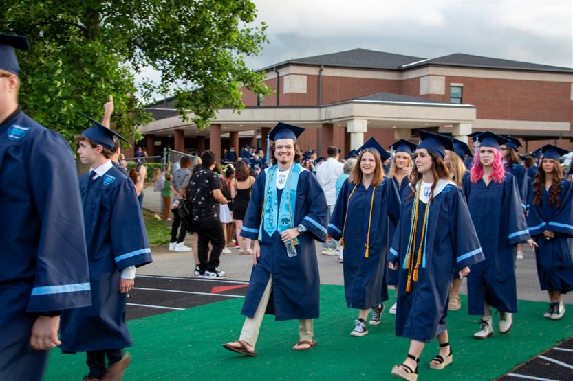 Students graduate outside on a football field